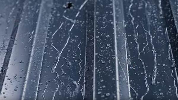 Nahaufnahme eines dunkelgrauen Dachblechs bedeckt mit Regentropen